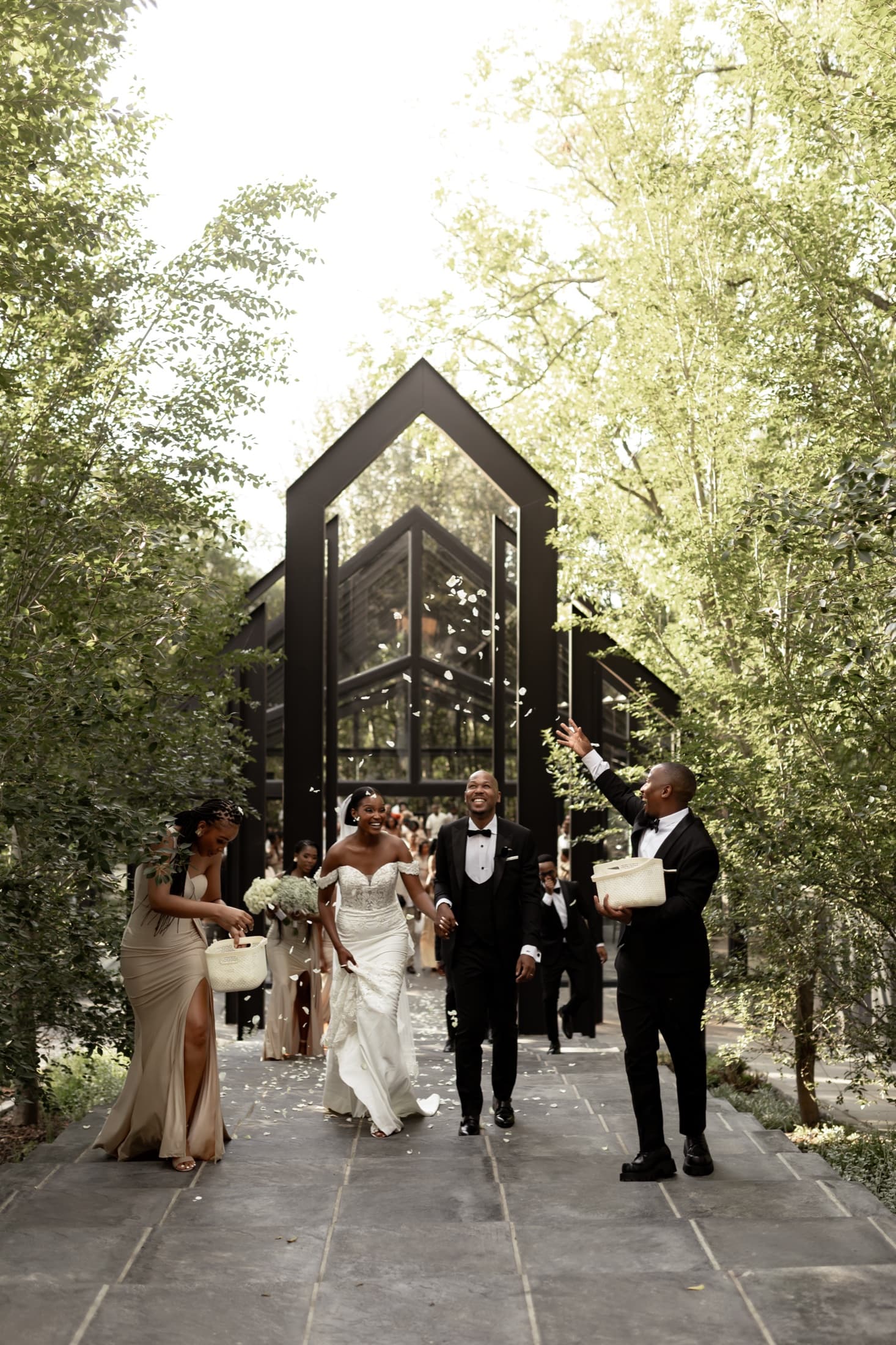 A couple leaving the glass chapel under confetti at Inimitable